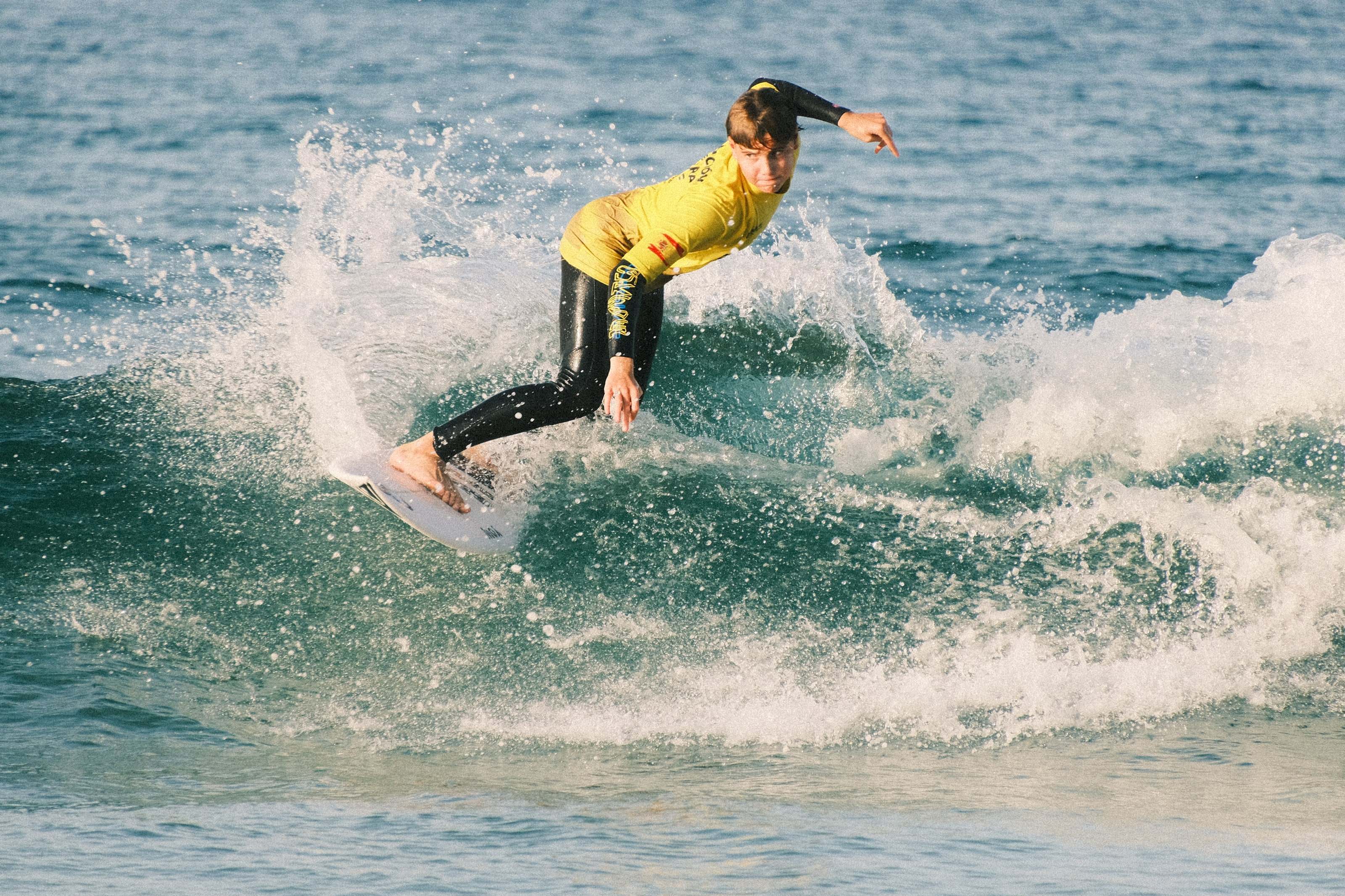 Young competitor in a yellow contest jersey hitting the lip, surf contest in San Vicente de la Barquera