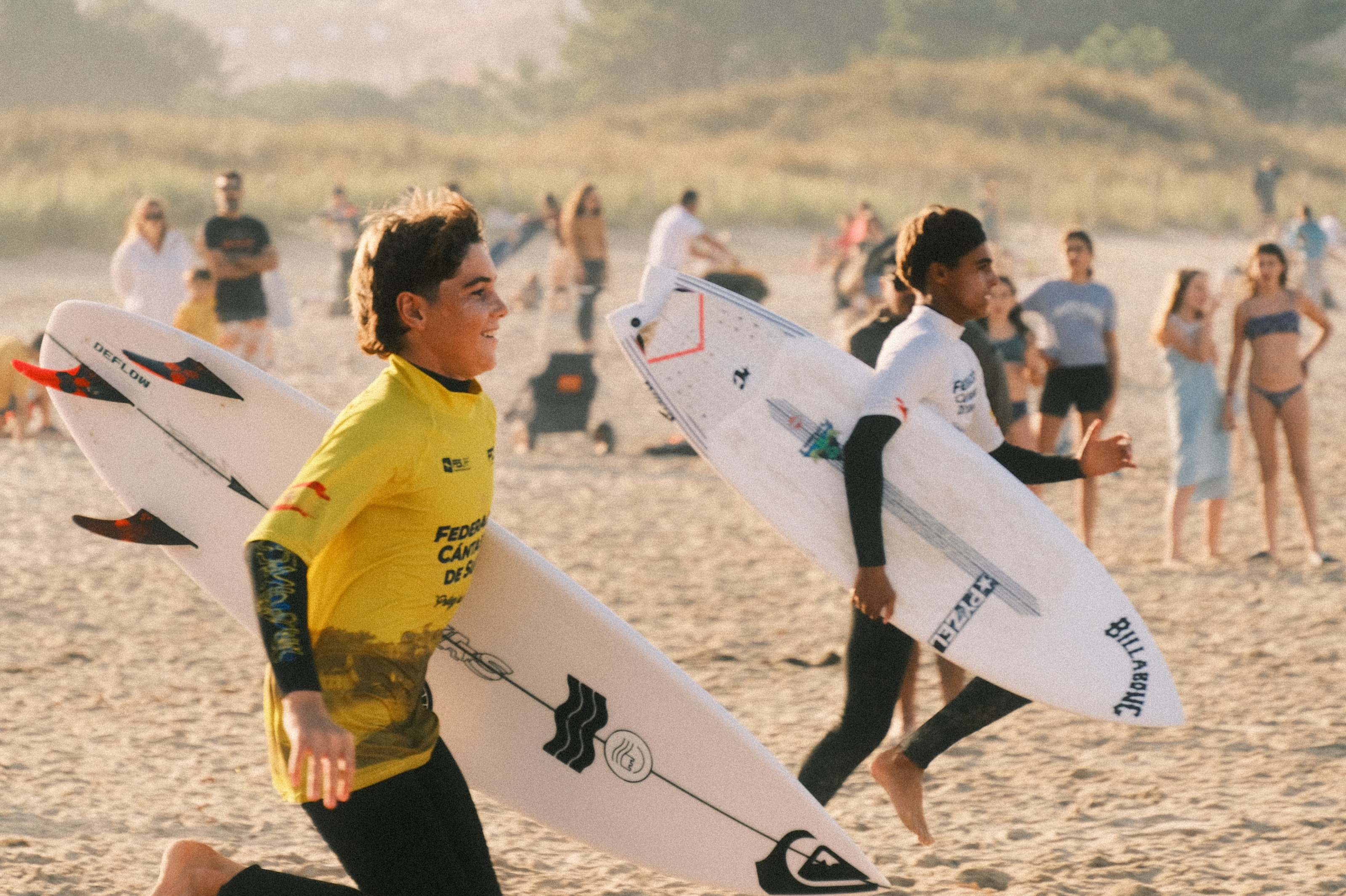 Two young surfers running to the water with their boards at a surf contest