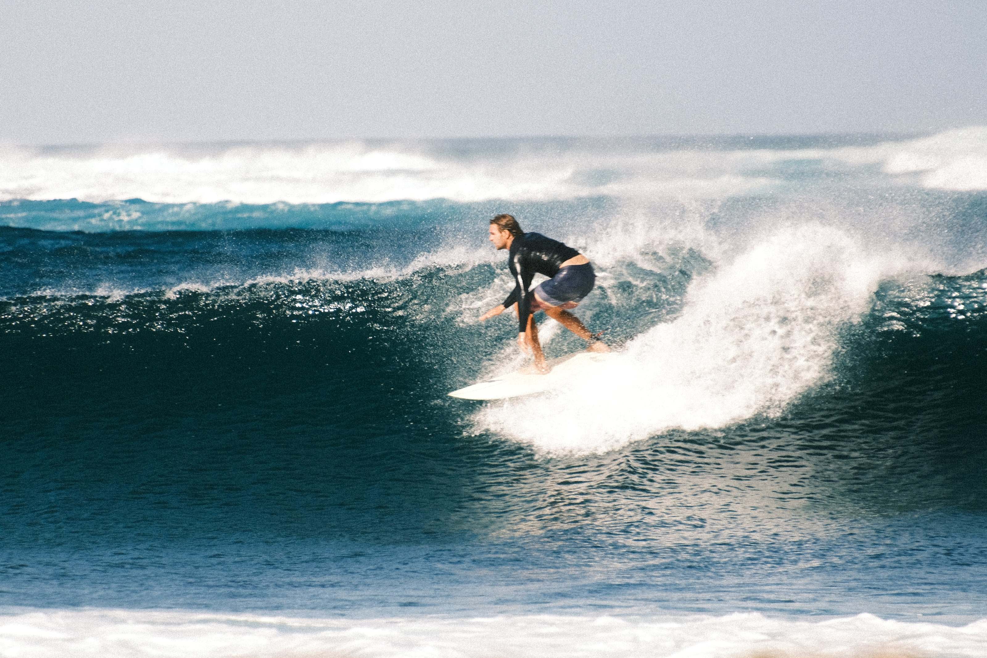 Surfer leaning into a bottom turn on a heavy blue wave in Fuerteventura